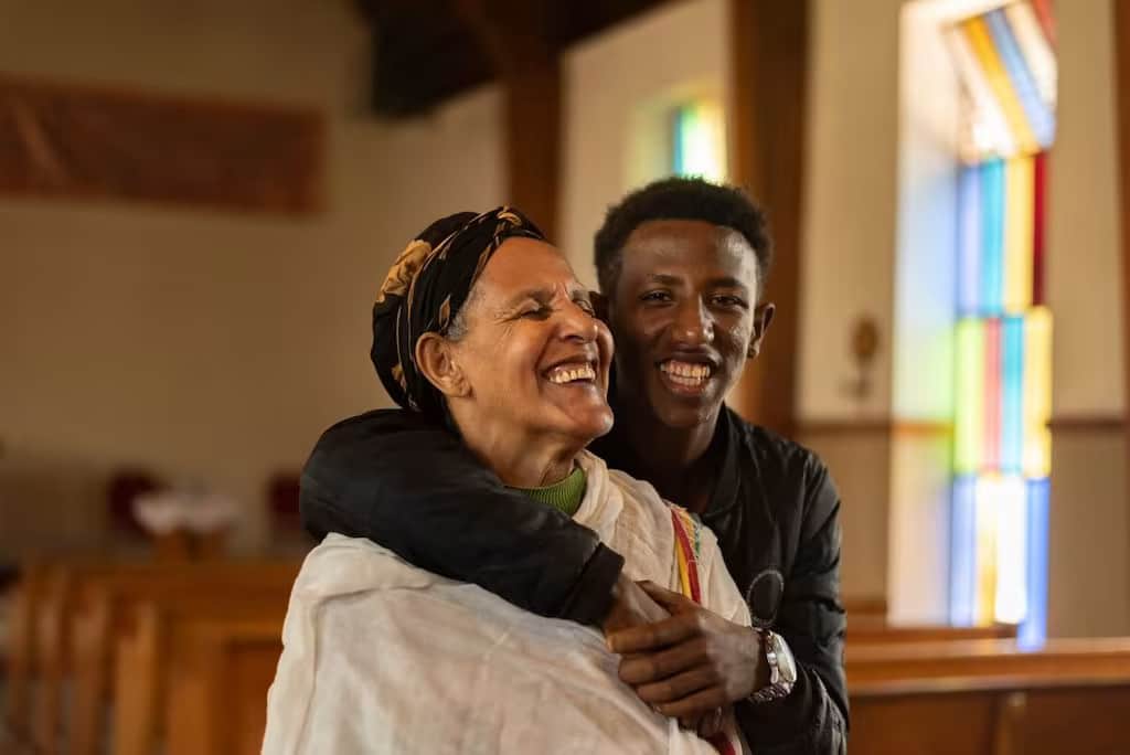 Un garçon éthiopien embrasse sa grand-mère. Ils sont assis dans une Eglise.