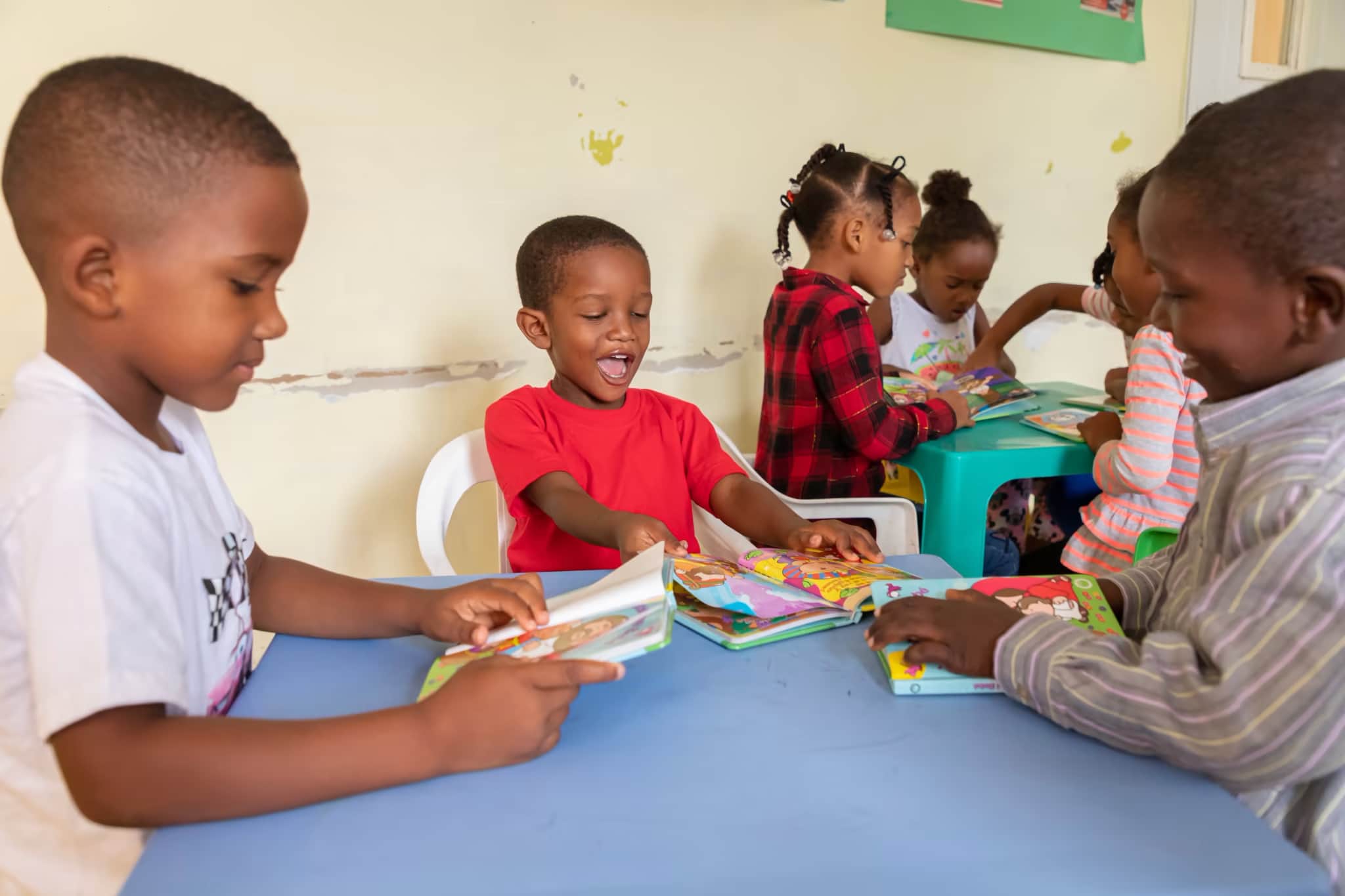 parrainage - Un groupe d'enfants assis autour d'une table en train de lire et de sourire.