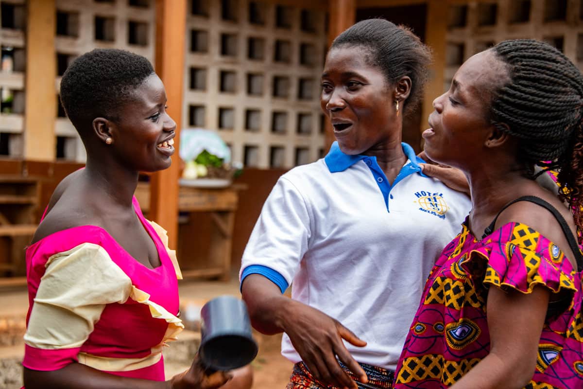 tre giovani donne ridono e chiacchierano in un centro Compassion in Togo