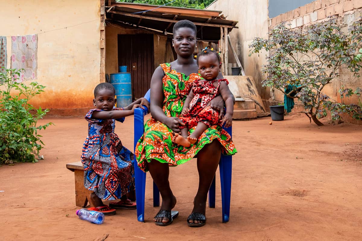 Une maman du Togo avec ses deux filles devant leur maison